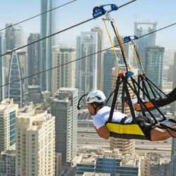 Person ziplining over the Dubai Marina with skyscrapers in the background.