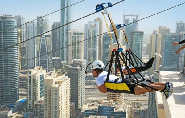 Person ziplining over the Dubai Marina with skyscrapers in the background.