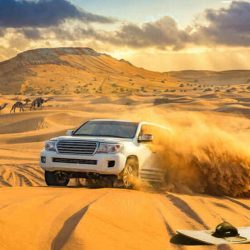 Morning Desert Safari Dubai with a 4x4 jeep driving on sand dunes against a backdrop of sunrise