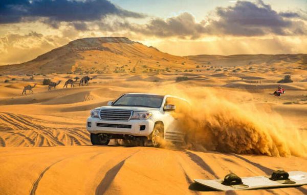 Morning Desert Safari Dubai with a 4x4 jeep driving on sand dunes against a backdrop of sunrise