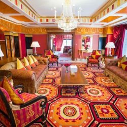 Opulent lobby area of Burj Al Arab with grand staircase, chandelier, and gold decor on the walls and floor.