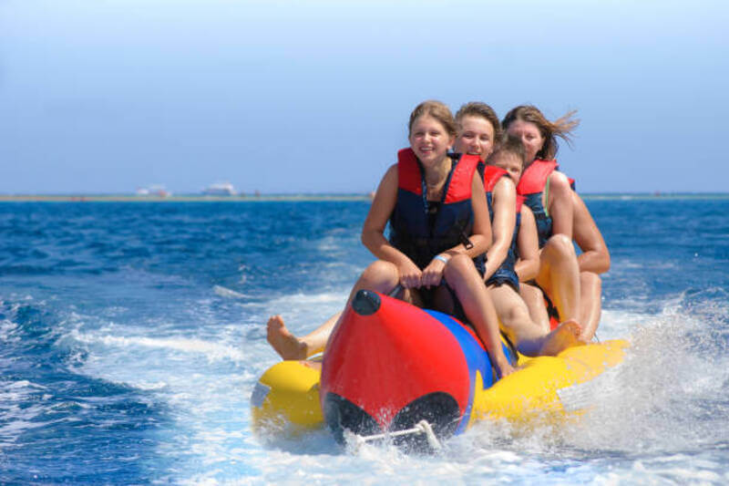 People ride on banana boat. Bright blue sea and clear sky. Happy vacation.