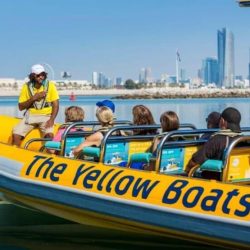 Yellow boat sailing through Dubai Marina with skyscrapers in the background.