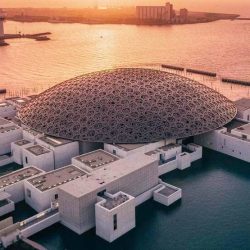 Alt text for the image of Louvre Museum Abu Dhabi could be "The iconic dome-shaped roof of the Louvre Museum Abu Dhabi, with the blue sky and a reflecting pool in the foreground."