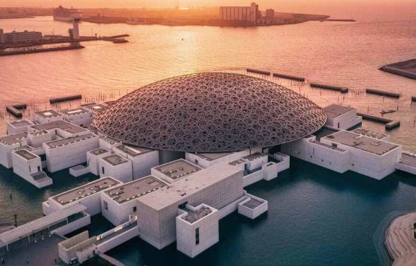 Alt text for the image of Louvre Museum Abu Dhabi could be "The iconic dome-shaped roof of the Louvre Museum Abu Dhabi, with the blue sky and a reflecting pool in the foreground."