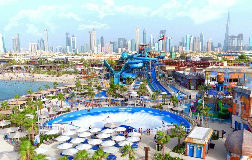 A group of people having fun on a thrilling water slide in Laguna Water Park Dubai, surrounded by clear blue water and palm trees.