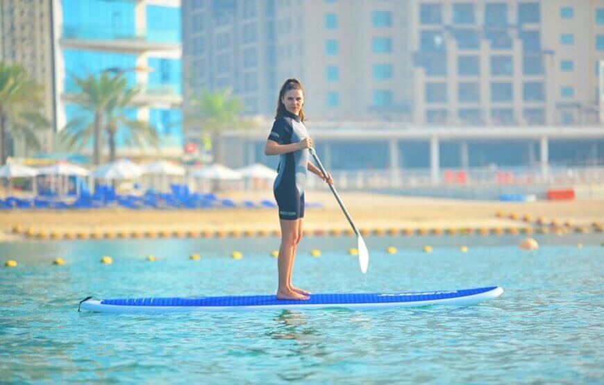 Person standing on a paddleboard in the calm waters of Dubai, with the city skyline in the background