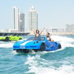 Alt text for the image of Jet Car Ride over the Gulf Ocean could be "A high-speed jet car flying over the calm blue waters of the Gulf Ocean, with a clear blue sky and sandy coastline in the background.